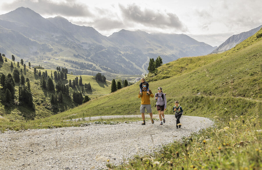Familie beim Wandern auf Bergweg in alpiner Landschaft