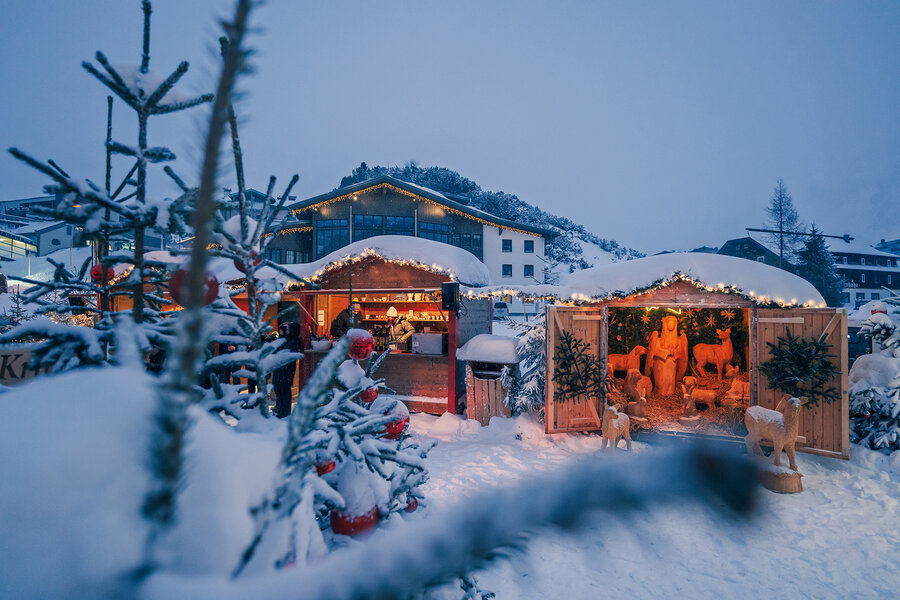 Festlich beleuchtete Adventhütten und eine traditionelle Weihnachtskrippe beim Tauernadvent, umgeben von verschneiten Tannen.