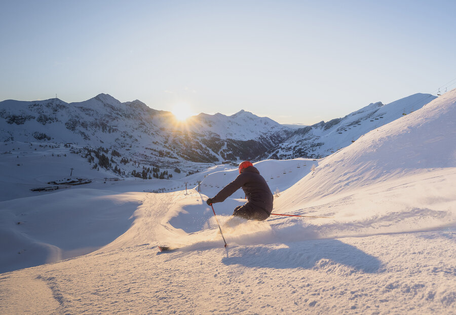 Skifahrer auf der Piste bei Sonnenaufgang in Obertauern
