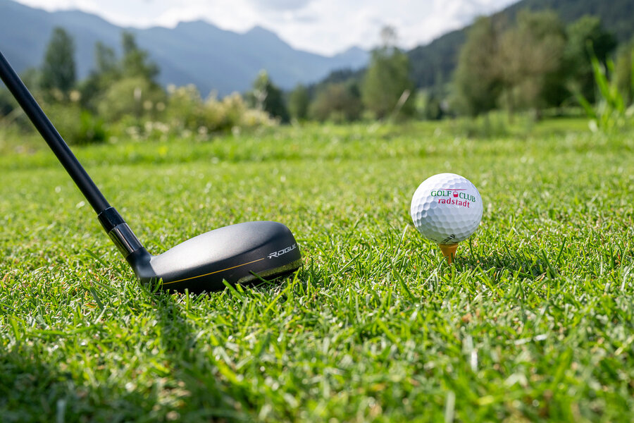 Golfball und Schläger auf dem Rasen eines Golfplatzes
