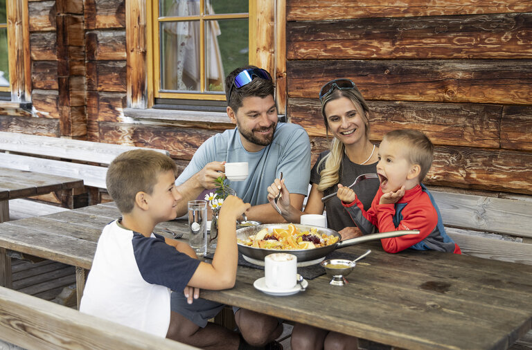 Familie genießt gemeinsames Essen auf Almhütte in Obertauern