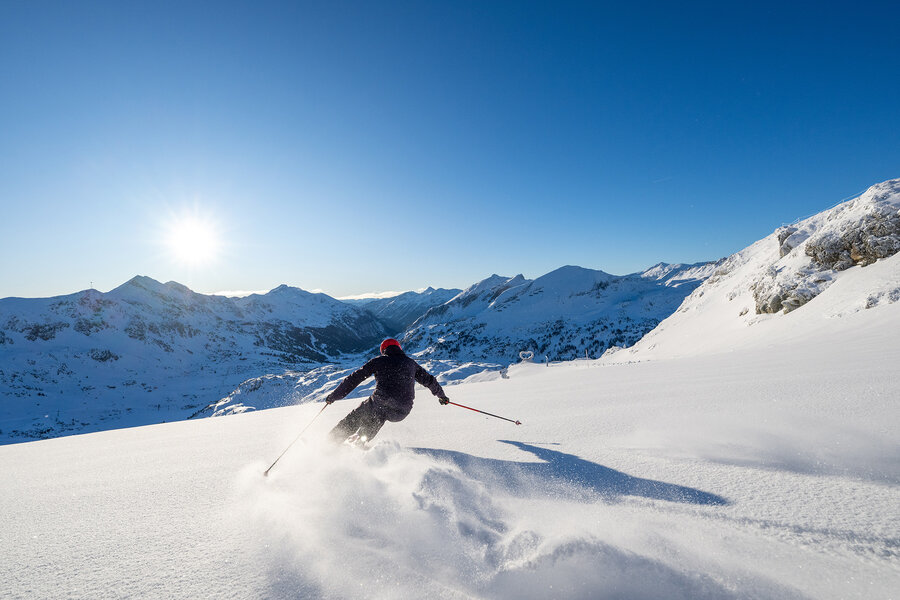 Skifahrer im Tiefschnee bei Sonnenschein in Obertauern