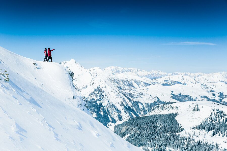 Zwei Snowboarder bestaunen die Landschaft beim Freeriden.