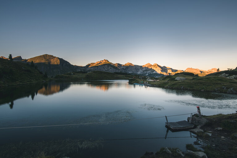 Krummschnabelsee in Obertauern mit Bergen im Hintergrund bei Sonnenuntergang.