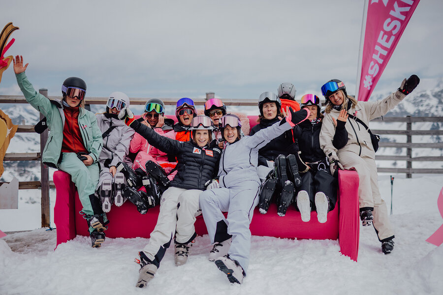 Gruppe von Skifahrerinnen auf pinkem Sofa im Schnee