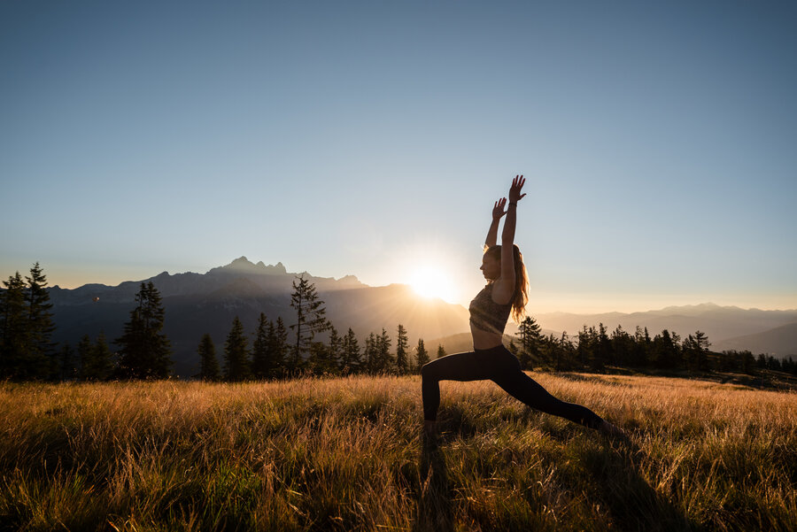 Frau praktiziert Yoga mit Bergkulisse von Obertauern in alpiner Umgebung