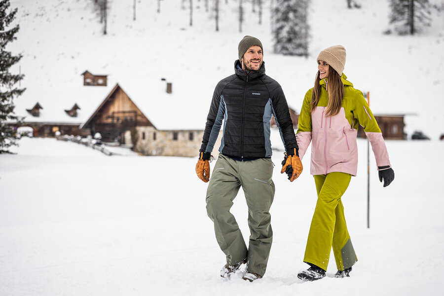 Personen beim Winterspaziergang auf der Gnadenalm im Schnee.