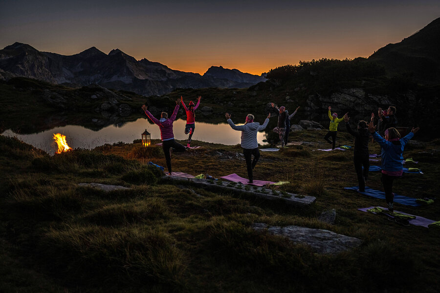 Yoga-Gruppe beim Bergyoga in Obertauern am See in der Morgendämmerung