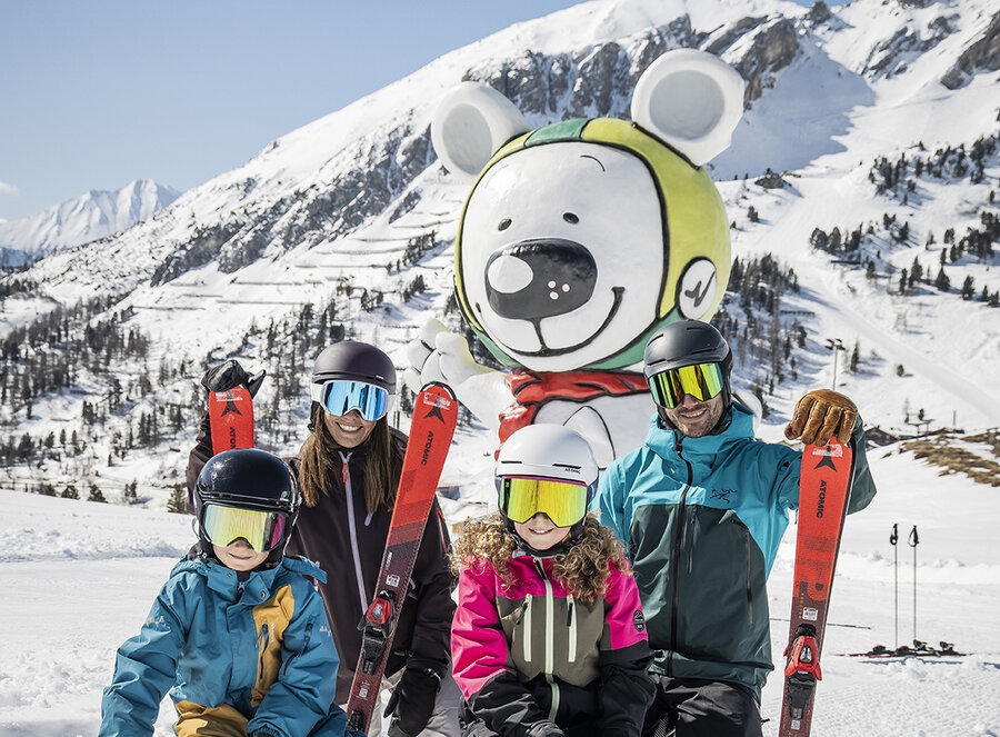 Familie posiert vor der Bibo-Bär-Statue in Obertauern.